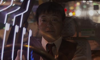 Movie still from “Like Someone in Love” (2012), directed by Abbas Kiarostami – A man wearing a suit and tie sitting in a car; Close Up shot, Low angle