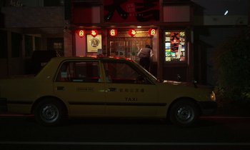 Movie still from “Like Someone in Love” (2012), directed by Abbas Kiarostami – A yellow taxi cab parked in front of a restaurant; Extreme Wide shot, Low angle