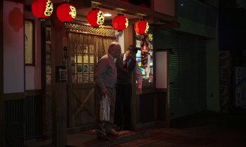 Movie still from “Like Someone in Love” (2012), directed by Abbas Kiarostami – Two men standing outside of a restaurant at night; Wide shot, Low angle