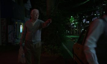 Movie still from “Like Someone in Love” (2012), directed by Abbas Kiarostami – An old man standing on the side of the road; Medium shot, Low angle