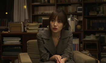 Movie still from “Like Someone in Love” (2012), directed by Abbas Kiarostami – A woman sitting in a chair in a room; Medium shot, Over the shoulder angle