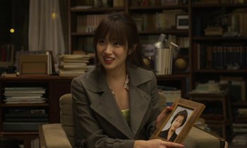 Movie still from “Like Someone in Love” (2012), directed by Abbas Kiarostami – A woman sitting in a chair holding a picture; Close Up shot, Over the shoulder angle
