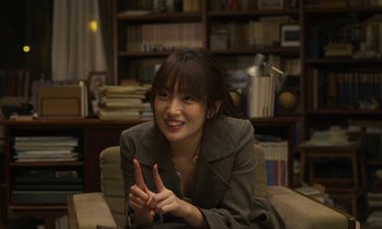 Movie still from “Like Someone in Love” (2012), directed by Abbas Kiarostami – A woman sitting in a chair smiling at the camera; Close Up shot, Over the shoulder angle