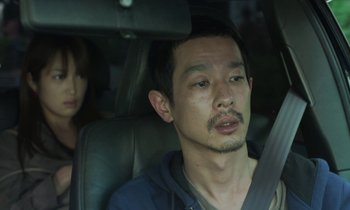 Movie still from “Like Someone in Love” (2012), directed by Abbas Kiarostami – A man sitting in the back seat of a car with a woman behind him; Close Up shot, Over the shoulder angle
