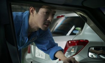 Movie still from “Like Someone in Love” (2012), directed by Abbas Kiarostami – A man working on a car in a garage; Close Up shot, Low angle