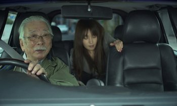 Movie still from “Like Someone in Love” (2012), directed by Abbas Kiarostami – An older man and a young woman in the back seat of a car; Medium shot, Over the shoulder angle