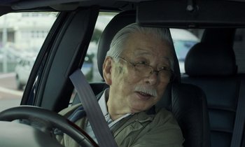 Movie still from “Like Someone in Love” (2012), directed by Abbas Kiarostami – An older man sitting in the driver's seat of a car; Close Up shot, Over the shoulder angle