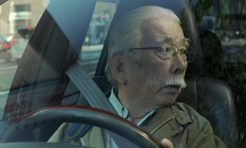 Movie still from “Like Someone in Love” (2012), directed by Abbas Kiarostami – An older man driving in a car with a beard; Close Up shot, Low angle