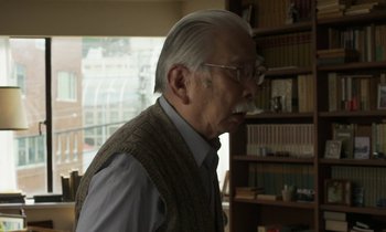 Movie still from “Like Someone in Love” (2012), directed by Abbas Kiarostami – An old man with a beard and glasses in a room; Close Up shot, Over the shoulder angle