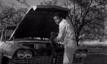 Movie still from “Lilies of the Field” (1963), directed by Ralph Nelson – A black and white photo of a man working on an old car; Medium shot, Low angle