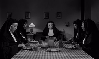 Movie still from “Lilies of the Field” (1963), directed by Ralph Nelson – A group of nuns sitting at a table with plates of food; Medium shot, High angle
