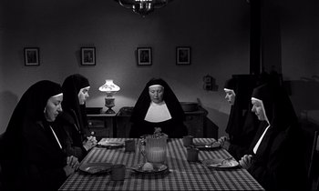 Movie still from “Lilies of the Field” (1963), directed by Ralph Nelson – A group of nuns sitting at a table with plates; Wide shot, High angle