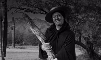 Movie still from “Lilies of the Field” (1963), directed by Ralph Nelson – A man holding a wooden stick in front of a tree; Medium shot, Low angle