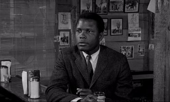 Movie still from “Lilies of the Field” (1963), directed by Ralph Nelson – A black and white photo of a man sitting at a table; Close Up shot, Low angle
