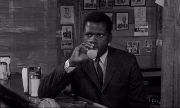 Movie still from “Lilies of the Field” (1963), directed by Ralph Nelson – A black and white photo of a man drinking a cup; Close Up shot, High angle