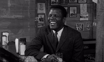 Movie still from “Lilies of the Field” (1963), directed by Ralph Nelson – A black and white photo of a man smiling; Medium shot, Low angle