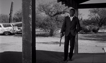 Movie still from “Lilies of the Field” (1963), directed by Ralph Nelson – A black and white photo of a man in a suit holding a baseball bat; Wide shot, Low angle