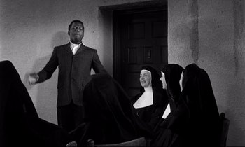 Movie still from “Lilies of the Field” (1963), directed by Ralph Nelson – A man in a suit and a woman in a nun's habit; Medium shot, Over the shoulder angle