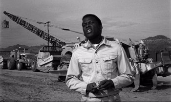 Movie still from “Lilies of the Field” (1963), directed by Ralph Nelson – A black and white photo of a man holding a cell phone; Medium shot, Low angle