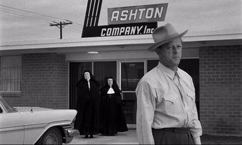 Movie still from “Lilies of the Field” (1963), directed by Ralph Nelson – A man standing in front of a building with two nuns; Wide shot, Low angle