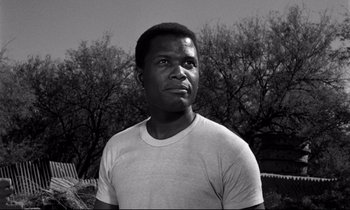 Movie still from “Lilies of the Field” (1963), directed by Ralph Nelson – A black and white photo of a man in front of trees; Close Up shot, Low angle