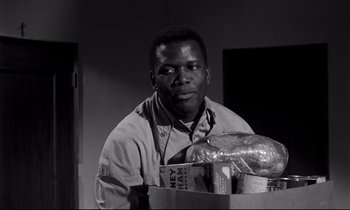 Movie still from “Lilies of the Field” (1963), directed by Ralph Nelson – A black and white photo of a man holding a box of food; Close Up shot, Over the shoulder angle