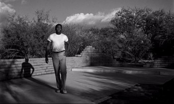 Movie still from “Lilies of the Field” (1963), directed by Ralph Nelson – A black and white photo of a man in a white shirt; Wide shot, Low angle