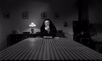 Movie still from “Lilies of the Field” (1963), directed by Ralph Nelson – A nun sitting at a table with a laptop; Medium shot, High angle