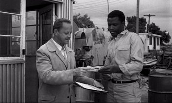 Movie still from “Lilies of the Field” (1963), directed by Ralph Nelson – Two men standing next to each other holding papers; Medium shot, Over the shoulder angle