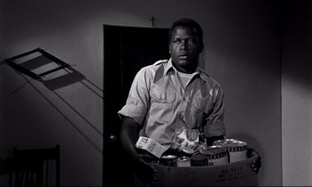Movie still from “Lilies of the Field” (1963), directed by Ralph Nelson – A black and white photo of a man holding a box of beer; Medium shot, Low angle