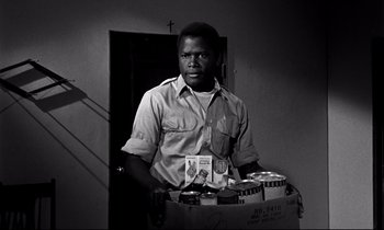 Movie still from “Lilies of the Field” (1963), directed by Ralph Nelson – A black and white photo of a man holding a box; Medium shot, Low angle