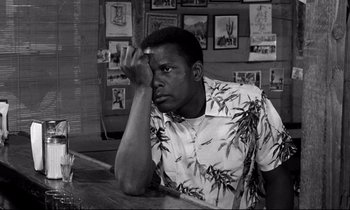 Movie still from “Lilies of the Field” (1963), directed by Ralph Nelson – A black and white photo of a man sitting at a table; Medium shot, Over the shoulder angle