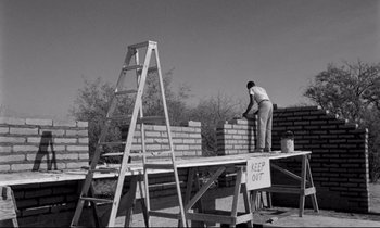 Movie still from “Lilies of the Field” (1963), directed by Ralph Nelson – A man standing on top of a ladder near a brick wall; Wide shot, Low angle