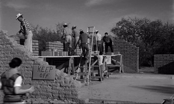 Movie still from “Lilies of the Field” (1963), directed by Ralph Nelson – A black and white photo of men working on a brick wall; Wide shot, Low angle