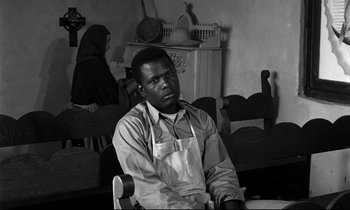 Movie still from “Lilies of the Field” (1963), directed by Ralph Nelson – A black and white photo of a man sitting in front of a woman; Medium shot, Over the shoulder angle