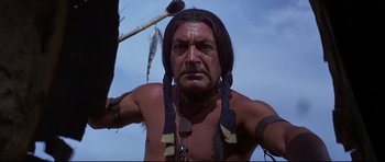 Movie still from “Little Big Man” (1970), directed by Arthur Penn – A man with long black hair holding a spear; Close Up shot, Low angle