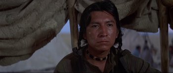 Movie still from “Little Big Man” (1970), directed by Arthur Penn – A native american man with a long black necklace; Close Up shot, Low angle