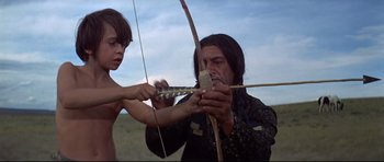 Movie still from “Little Big Man” (1970), directed by Arthur Penn – A man and a boy holding a bow and arrow; Medium shot, Low angle