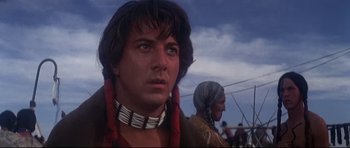 Movie still from “Little Big Man” (1970), directed by Arthur Penn – A person wearing a necklace with a sky in the background; Close Up shot, Low angle