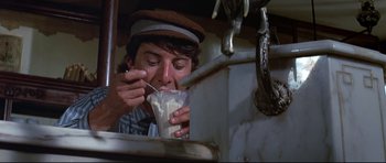Movie still from “Little Big Man” (1970), directed by Arthur Penn – A man in a hat is eating something in a cup; Close Up shot, High angle