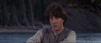 Movie still from “Little Big Man” (1970), directed by Arthur Penn – A man with long brown hair sitting in front of a forest; Close Up shot, Low angle