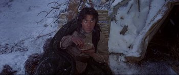 Movie still from “Little Big Man” (1970), directed by Arthur Penn – A man sitting in the snow holding a bowl of food; Medium shot, Low angle