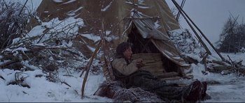 Movie still from “Little Big Man” (1970), directed by Arthur Penn – A man sitting in the snow next to a tent; Wide shot, High angle