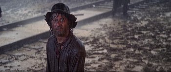 Movie still from “Little Big Man” (1970), directed by Arthur Penn – A man with a hat and a beard standing in the rain; Medium shot, Low angle