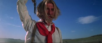 Movie still from “Little Big Man” (1970), directed by Arthur Penn – A man with long hair and a red neck tie holding a gun; Medium shot, Low angle