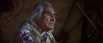 Movie still from “Little Big Man” (1970), directed by Arthur Penn – An older man with long white hair wearing a native american outfit; Close Up shot, Low angle