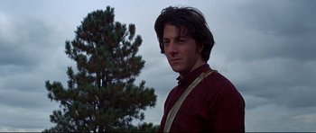 Movie still from “Little Big Man” (1970), directed by Arthur Penn – A man in a red shirt is standing in front of a tree; Close Up shot, Low angle