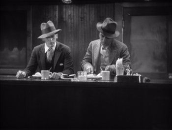 Movie still from “Little Caesar” (1931), directed by Mervyn LeRoy – A couple of men sitting at a long table; Medium shot, High angle