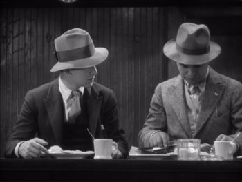 Movie still from “Little Caesar” (1931), directed by Mervyn LeRoy – A couple of men sitting next to each other at a table; Medium shot, High angle