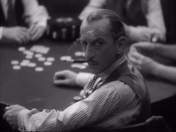Movie still from “Little Caesar” (1931), directed by Mervyn LeRoy – A black and white photo of a man sitting at a poker table; Close Up shot, Over the shoulder angle